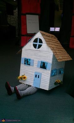 a woman sitting on the floor in front of a doll house with her legs up