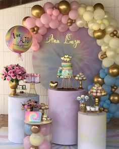 there is a cake and balloons on display at this birthday party with pastel colors