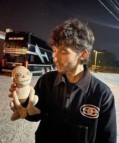 a man holding a small stuffed animal in his right hand and looking at the camera