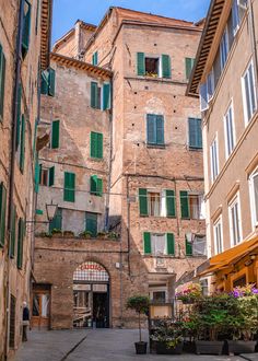 an alley way with several buildings and green shutters