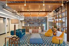 a large room with many different colored chairs and tables on the floor in front of a wine rack