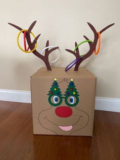 a cardboard box with reindeer's head painted on it and some scissors sticking out of the top