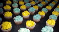 several cupcakes with yellow and blue frosting on the top are arranged in rows