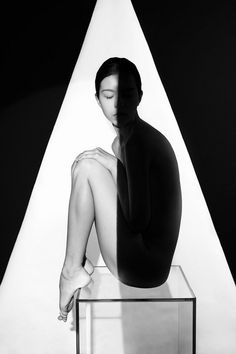 a black and white photo of a woman sitting on top of a table with her eyes closed