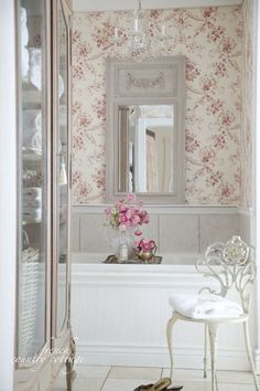 a white sink sitting under a bathroom mirror next to a bath tub with a vase on it