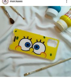 a phone case with the face of a cartoon character painted on it next to paintbrushes