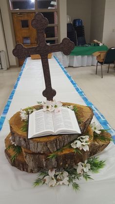 an open book is on top of a tree stump with a cross in the middle