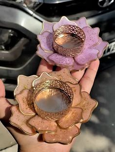 two pink and gold flower shaped candlesticks in front of a silver car on the street