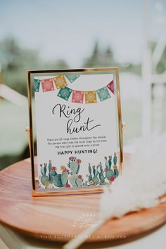 a card and gift box sitting on top of a wooden table next to a white feather