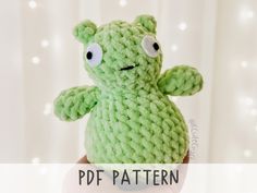 a green crocheted stuffed animal with big eyes