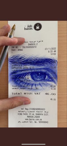 a person holding a pen over a paper with a blue eye on it and the words total with vat