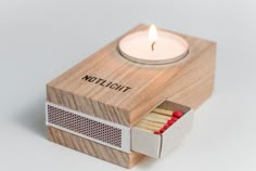 a matchbox with matches and a lit candle in it that says,'thichlott '