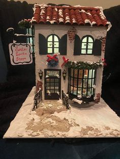 a white house with red roof and shutters on the front is decorated for christmas