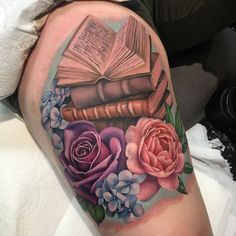 a tattoo with books and flowers on it