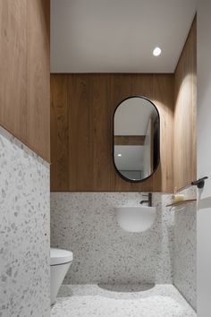 a bathroom with a sink, mirror and wooden paneling on the wall behind it