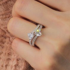 a woman's hand holding a ring with two diamonds on it and the middle finger