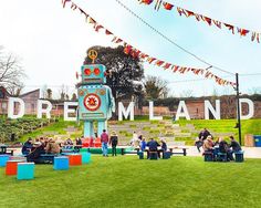 people are sitting on benches in front of a sign that reads dreamland with flags and bunting