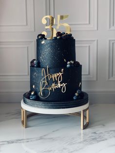 a three tiered black and gold birthday cake with the number fifteen on it's side