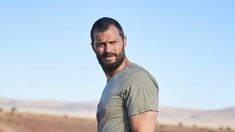 a man standing in the middle of a desert with his hands on his hips and looking at the camera