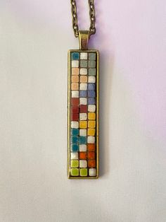 a multicolored necklace is shown on a white surface with a chain attached to it