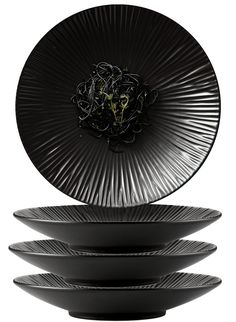 four black plates stacked on top of each other in front of a white background with an image of a flower