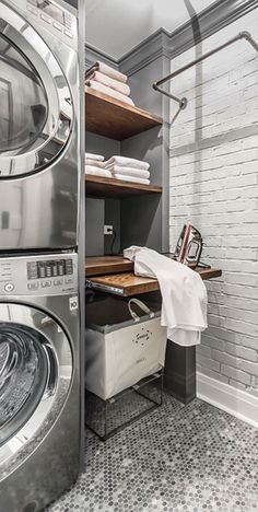 a washer and dryer in a room with white brick walls, tiled flooring and open shelving