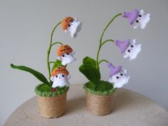 three small potted plants with tiny knitted animals on them