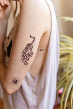 a woman with a tiger tattoo on her left arm and right arm behind her head