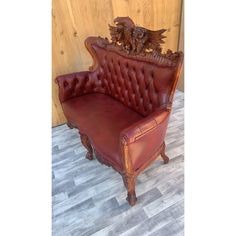 a red leather chair with an intricate carved back and arm rests against a wood paneled wall