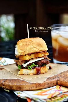 a sandwich sitting on top of a wooden cutting board next to a glass of soda