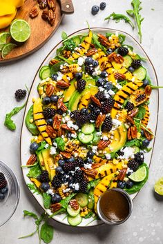 a large plate filled with fruit and vegetables on top of a white table next to other plates