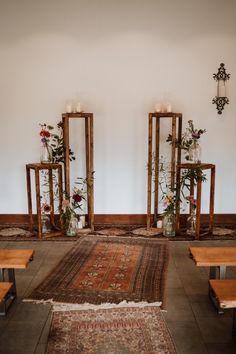 an area with benches, mirrors and flowers on the floor in front of a white wall