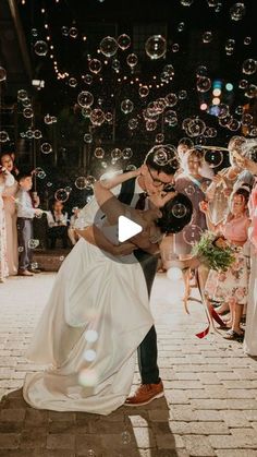 a bride and groom are kissing in front of bubbles as they fly through the air