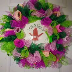 a purple and green mesh wreath hanging on a door with the words fish & floss