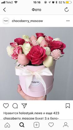 a person holding a pink and white box with flowers in it