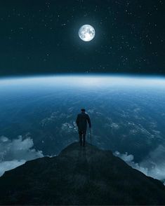 a man standing on top of a mountain looking at the moon