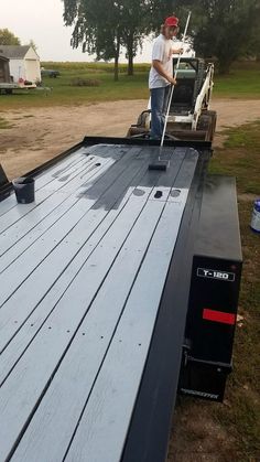 a man standing on the back of a flatbed trailer with a broom in his hand