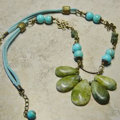 "Graduated size olive green new jade tear drop shaped beads are linked in antique brass wire accented with antique brass beads. The length of the necklace features turquoise magnesite beaded links, green serpentine beaded links and antique brass Celtic knot filigree. Beaded segments are linked on aqua blue suede cording accented with antique brass beads. There is a lobster claw closure on the necklace. Great casual rustic look. The length of the necklace is 21\" with a 1 1/2\" extension chain fo Adjustable Bohemian Jade Jewelry, Bohemian Beaded Jade Necklaces, Bohemian Jade Beaded Necklaces, Bohemian Beaded Jade Necklace, Bohemian Teardrop Brass Necklace, Bohemian Brass Teardrop Pendant Jewelry, Bohemian Beaded Necklaces With Teardrop Natural Stones, Turquoise Jade Beaded Bohemian Necklace, Bohemian Turquoise Jade Beaded Necklaces