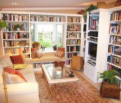 a living room filled with lots of furniture and bookshelves next to a window