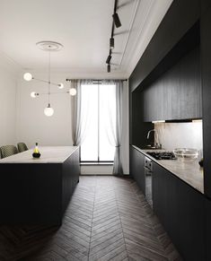 an empty kitchen with black cabinets and wood flooring is seen in this image from the living room