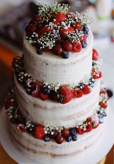 a three tiered cake with berries and sprinkles on the top layer