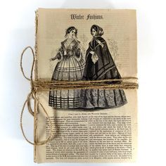 an old book is wrapped in twine and has two women's dresses on it