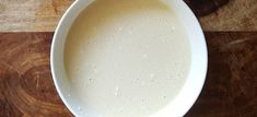 a white bowl filled with liquid on top of a wooden table