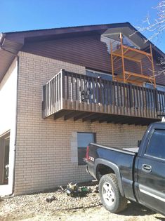 a truck parked in front of a building with a ladder on it's roof