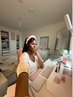 a woman sitting at a desk in front of a laptop computer with a pink headband on