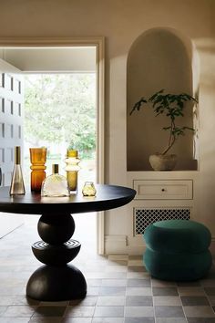 a dining room table with vases and bottles on it in front of an open door