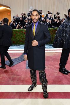 a man in a suit and tie standing on a red carpet with cameras around him