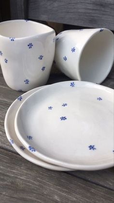 three white dishes with blue flowers on them sitting on a wooden table next to each other