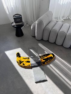 a yellow and black banana laying on the floor in a room with white curtains, sofas and other furniture