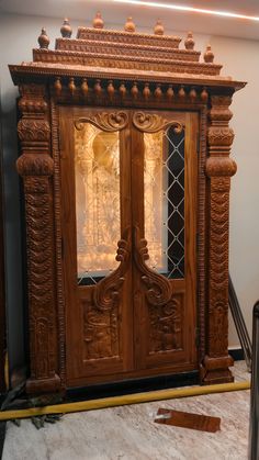 an ornate wooden armoire with glass doors and carvings on the front, in a room that is being remodeled